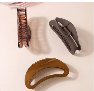 Détail de trois grandes pinces à cheveux ovales en ambre, marron et caramel mat
