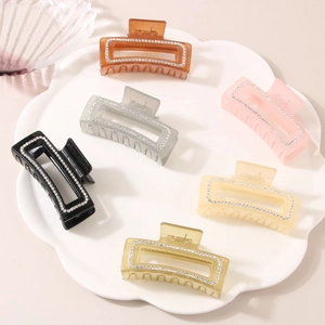 Dettaglio di 6 mollette per capelli quadrate colorate con strass su un vassoio