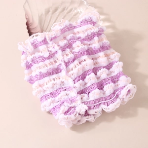 Detail of purple and white elastic lace headband texture with pom-poms on a tray