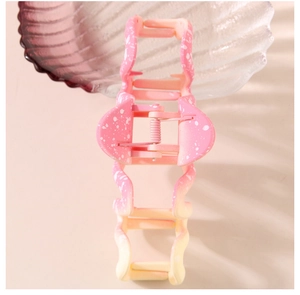 Detailed macro view of large wave hair claw with pink gradient and ink splatter texture
