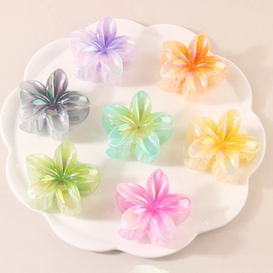 Macro shot of 7 colorful iridescent flower hair claws arranged in a white decorative tray