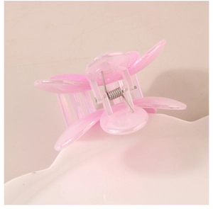 Gros plan détaillé d'une pince à cheveux fleur rose irisée sur un plateau décoratif blanc