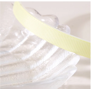 Close-up of 1cm yellow grosgrain ribbon texture on a decorative glass shell plate