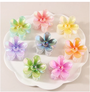 Macro de 8 pinces à cheveux colorées en forme de fleurs avec fini nacré sur une assiette blanche