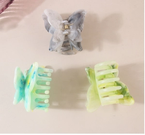 Detailed close-up of butterfly hair claw clips in marble and colorful acetate patterns
