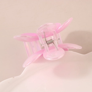 Pince à cheveux fleur rose translucide effet nacré posée sur un plateau en céramique