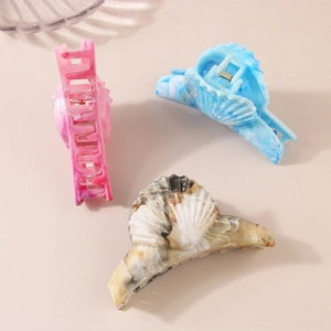Three shell-shaped marble pattern hair claw clips in pink, blue, and brown resin finishes