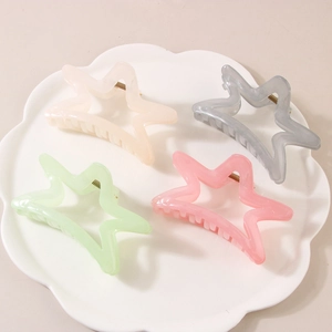 Star-shaped hair claw clips in pastel resin colors displayed on a white porcelain tray