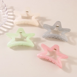 Detail shot of four star-shaped shark hair clips in cream, green, blue and pink pastel colors