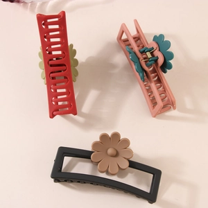 Three matte rectangular hair claws with daisy accents in red, pink, and black colors