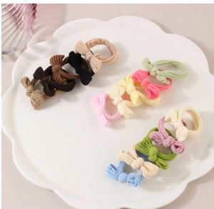 Détail de chouchous à nœuds élastiques en plusieurs couleurs sur une assiette blanche