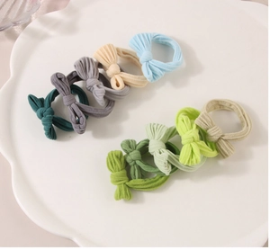 Détails de chouchous élastiques avec nœuds en couleurs variées sur un plateau blanc