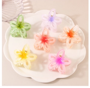 Detail view of hollow gradient flower hair claws in six vibrant colors on a white tray