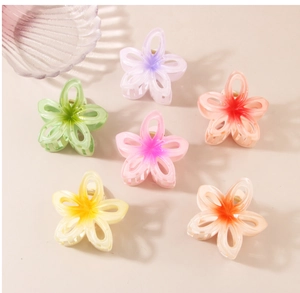 Flat lay of gradient resin flower hair claws in multiple colors on a soft beige background