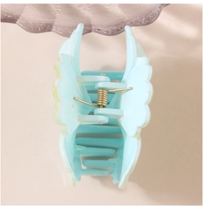 Detail view of light blue shell-shaped hair claw clip with golden metal spring