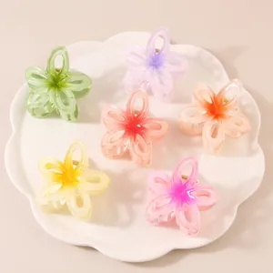 Set of six gradient flower hair claws in multiple colors on a white ceramic tray