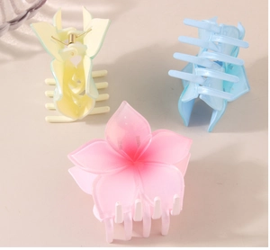 Detailed view of translucent plumeria hair claws in gradient pink, blue and green colors
