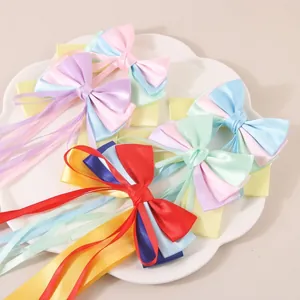 Barrettes à cheveux à long ruban de satin aux couleurs vives sur un plateau blanc