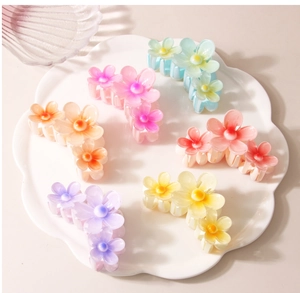 Détail de pinces à cheveux florales colorées en six teintes sur un plateau blanc