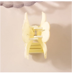 Detail view of cream yellow flower hair claw clip with golden metal spring for elegant updo