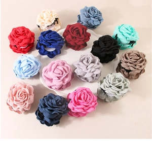 Detail view of colorful fabric rose hair claws in various shades on a white tray