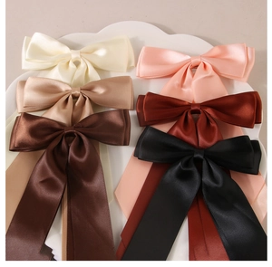 Set of satin bow hair clips with long ribbons in six assorted neutral colors on a tray