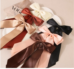 Detail of multi-color large satin ribbon bow hair clips on a white ceramic tray