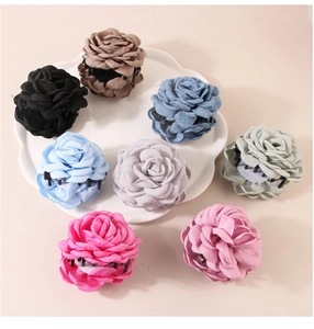 Flat lay of colorful fabric rose flower hair claws on a decorative cloud ceramic plate