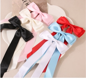 Detail von fünf Satin-Schleifen-Haarspangen mit langen Bändern auf einem Dekotablett