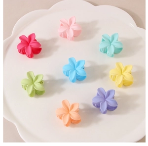 Makroaufnahme von 8 matten Blumen-Haarklammern in Pastellfarben auf weißem Tablett
