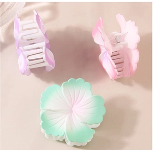 Detailed top view of three gradient matte flower hair claws in purple pink and green