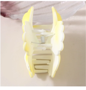 Detail view of flower hair claw clip with yellow and white gradient petals and metal spring