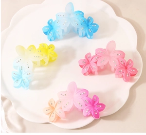 Detail view of four gradient flower hair claws with rhinestones on a white tray