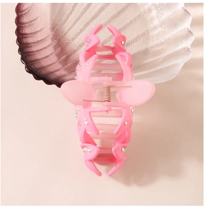 Detailed view of pink matte hair claw clip with rhinestones and metal spring