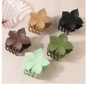 Detail von fünf matten Blumen-Haarklammern in dezenten Farben wie Grün, Braun und Beige