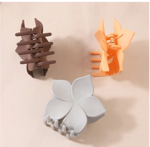 Detailansicht der blumenförmigen Haarklammern mit mattem Finish in Braun, Orange und Grau