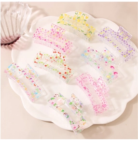 Macro shot of large floral printed hair claws in various patterns on a white tray