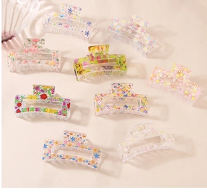 Detailed view of nine transparent acrylic hair claw clips with various floral prints