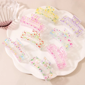 Set of 8 transparent acrylic hair claws with colorful fruit and floral prints in a dish