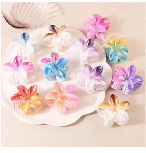 Iridescent flower claw clips with pearly finish displayed on white ceramic plate