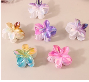Detailed view of six pearlescent plumeria flower hair claws in gradient pastel colors