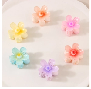 Gros plan de six pinces à cheveux fleurs colorées aux tons macaron sur un plat