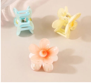 Vue détaillée de trois pinces à cheveux fleurs mates en bleu, jaune et couleur pêche