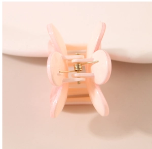 Vue macro d'une pince à cheveux rose clair avec mécanisme à ressort en métal doré durable