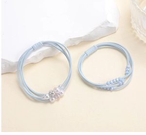 Detail of light blue elastic hair ties with pearl flower and beaded accents