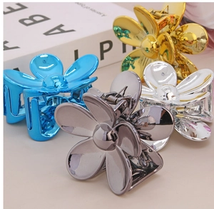 Dettaglio di quattro mollette a fiore metallizzate in blu, oro, argento e bianco perla