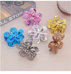 Top view of six metallic flower hair claws in pink, gold, blue, silver and grey colors