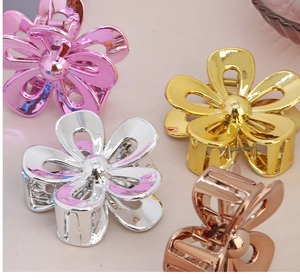 Detail view of four metallic floral hair claws in pink, gold, silver, and rose gold