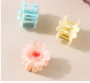 Détail de petites pinces à cheveux en forme de fleur colorées en rose, jaune et bleu