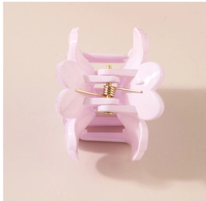 Détail d'une pince à cheveux rose clair en forme de cœur avec ressort doré